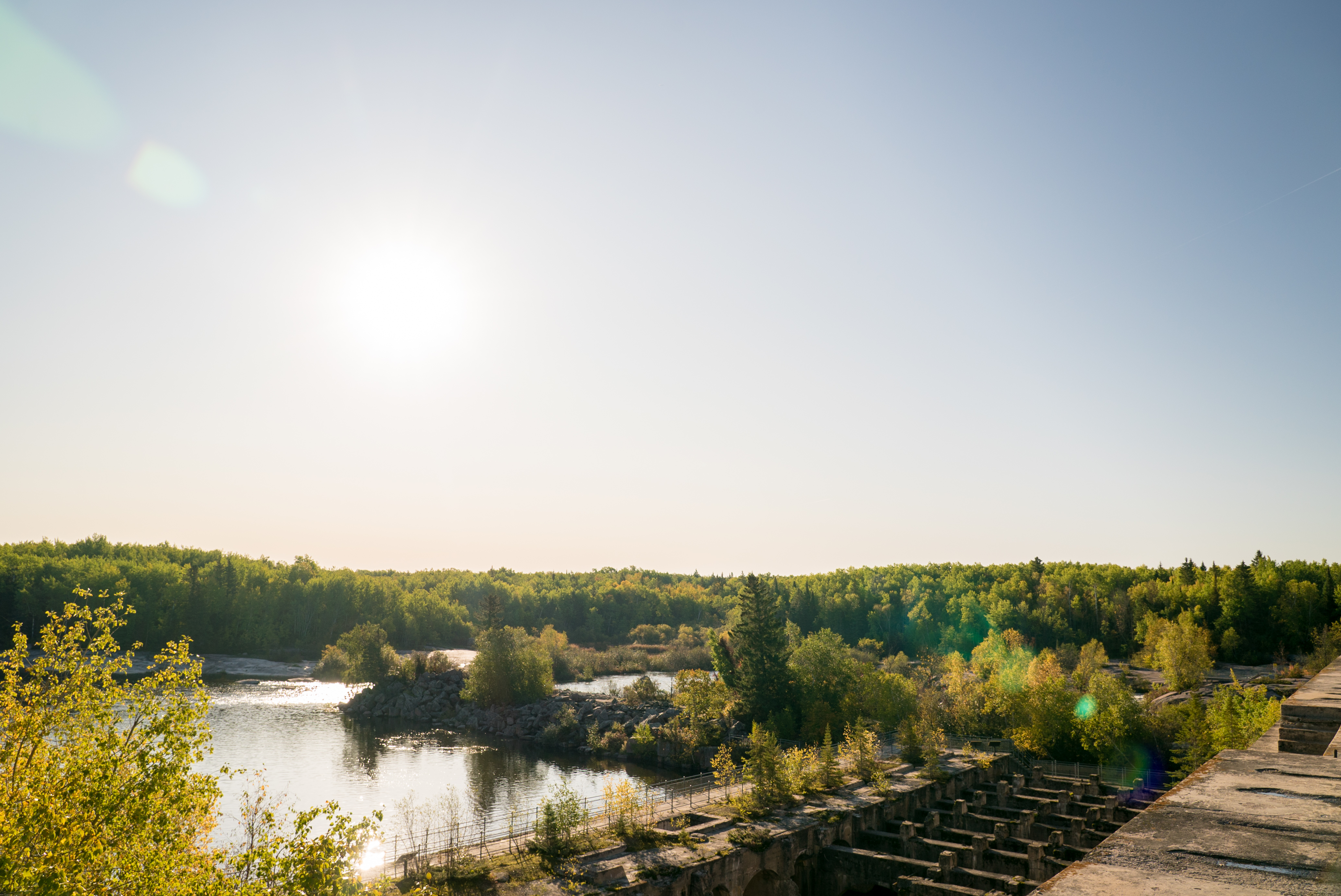 View of trees along the Winnipeg River and old concrete ruins of the Pinawa Dam