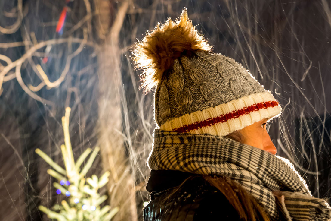 Woman with a toque and scarf standing on a snowy night