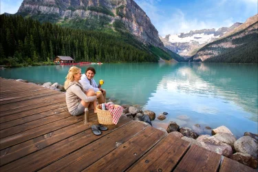 A couple indulges in a picnic on the dock overlooking Lake Louise
