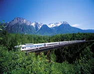 VIA Rail train going over the bridge through a forest in the mountains