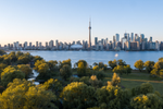 Toronto’s city skyline is across from Lake Ontario and a green park with trees  