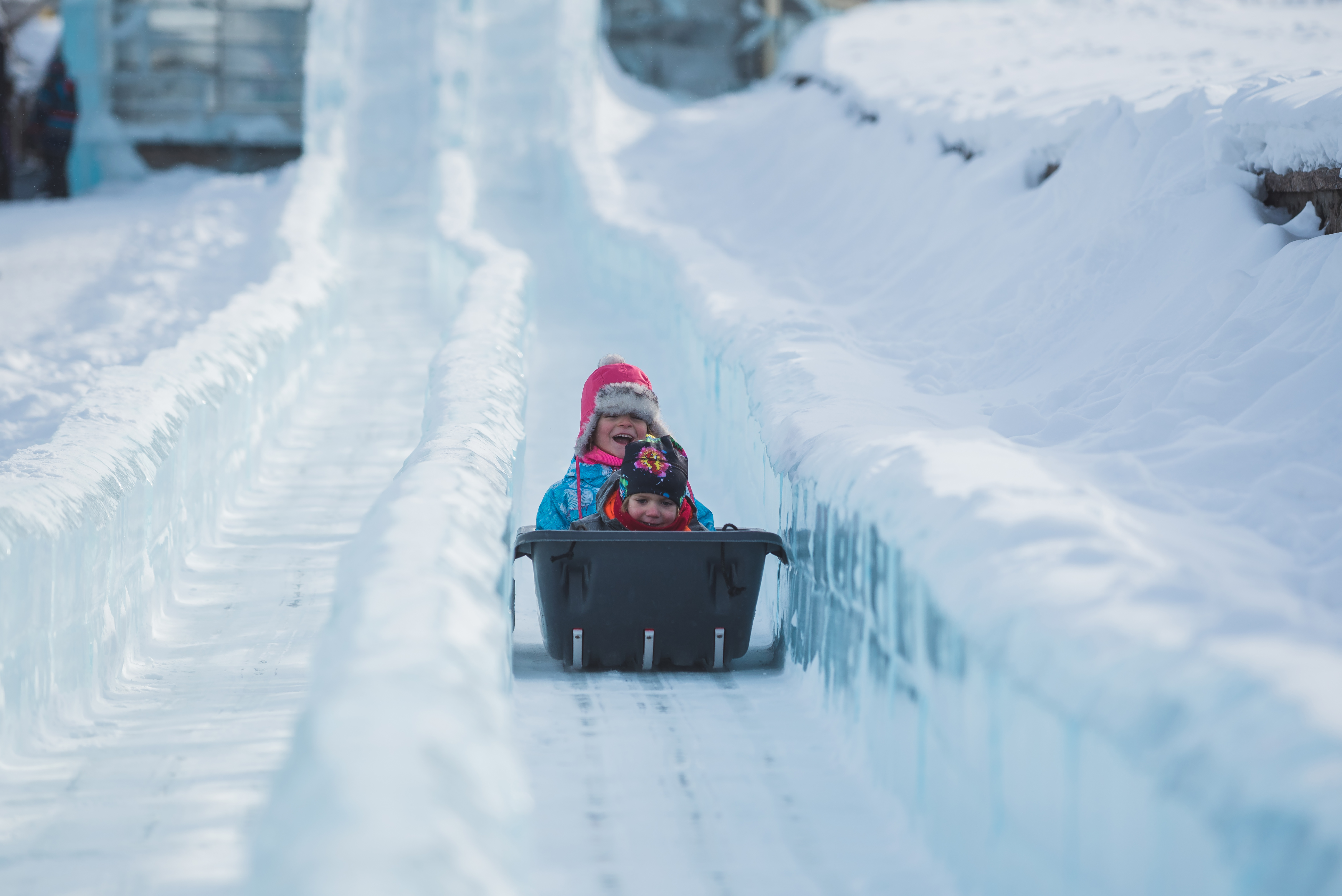 Small children sliding down an ice slide in a toboggan at the Quebec Winter Carnival ice palace