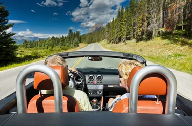 Couple in a convertible driving through Banff National Park in Alberta