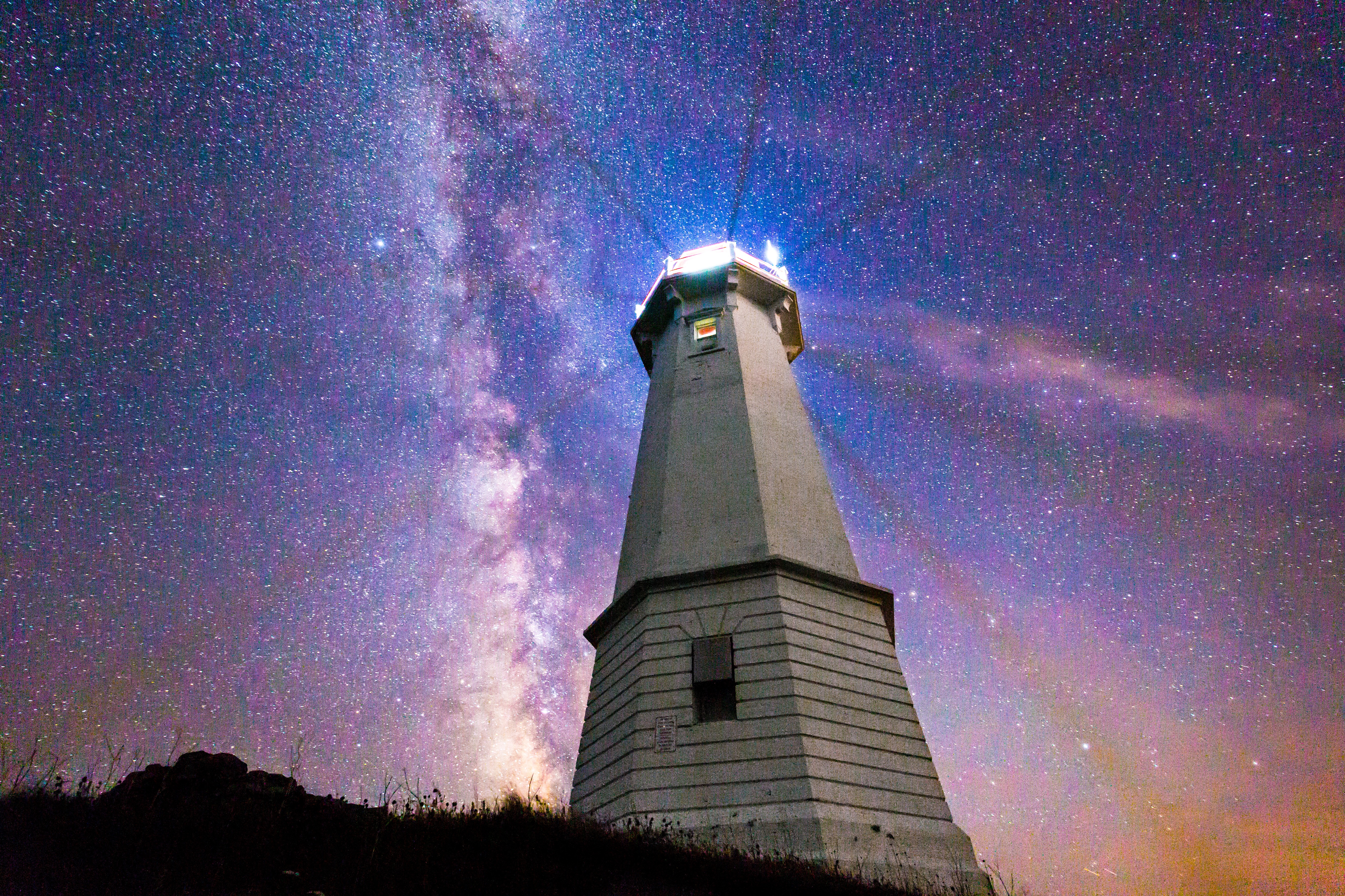 Louisbourg Lighthouse on a starry night near Atlantic Ocean and Nova Scotia's Louisbourg harbour