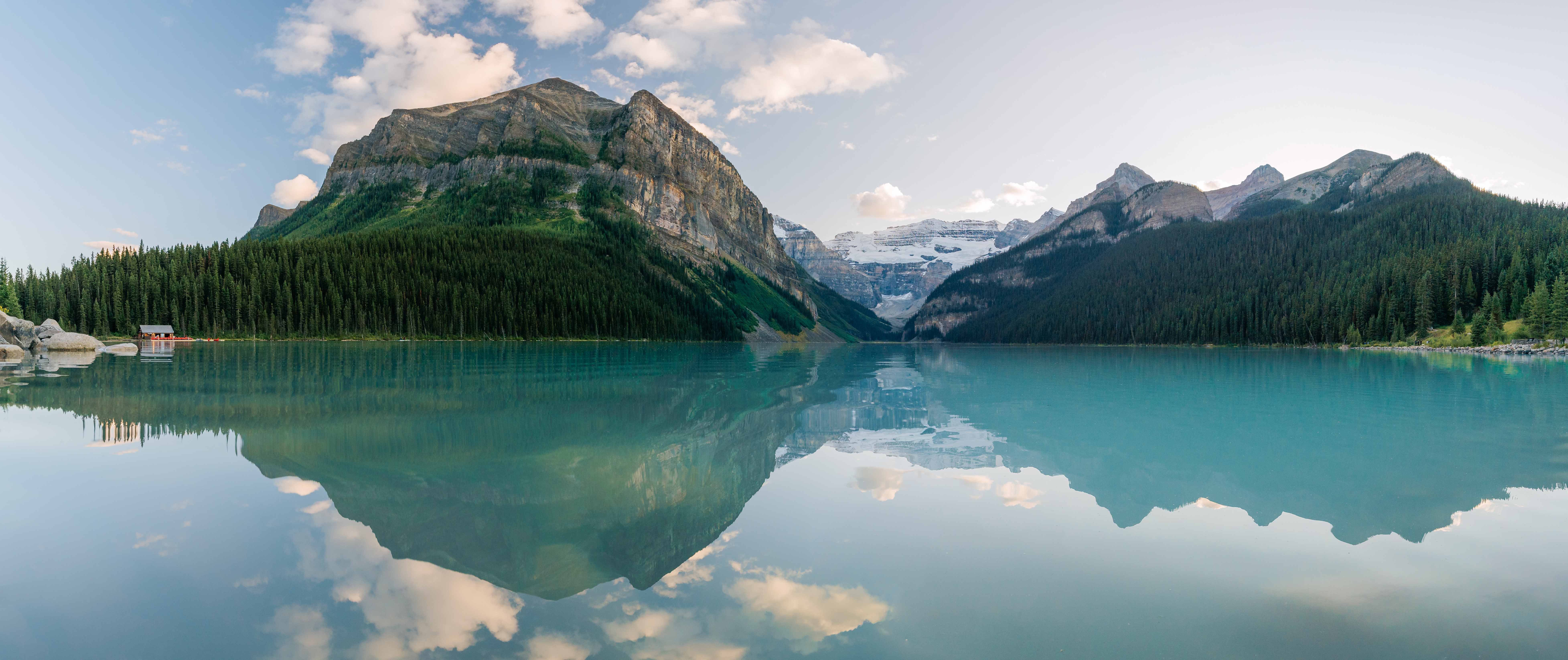 Lake Louise and jade eroded glacial silt waters appear still and reflect cream coloured clouds and Fairview Mountains famous peaks