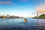 Two men paddle a kayak in city harbour and by Halifax Waterfront and Georges Island National Historic Site