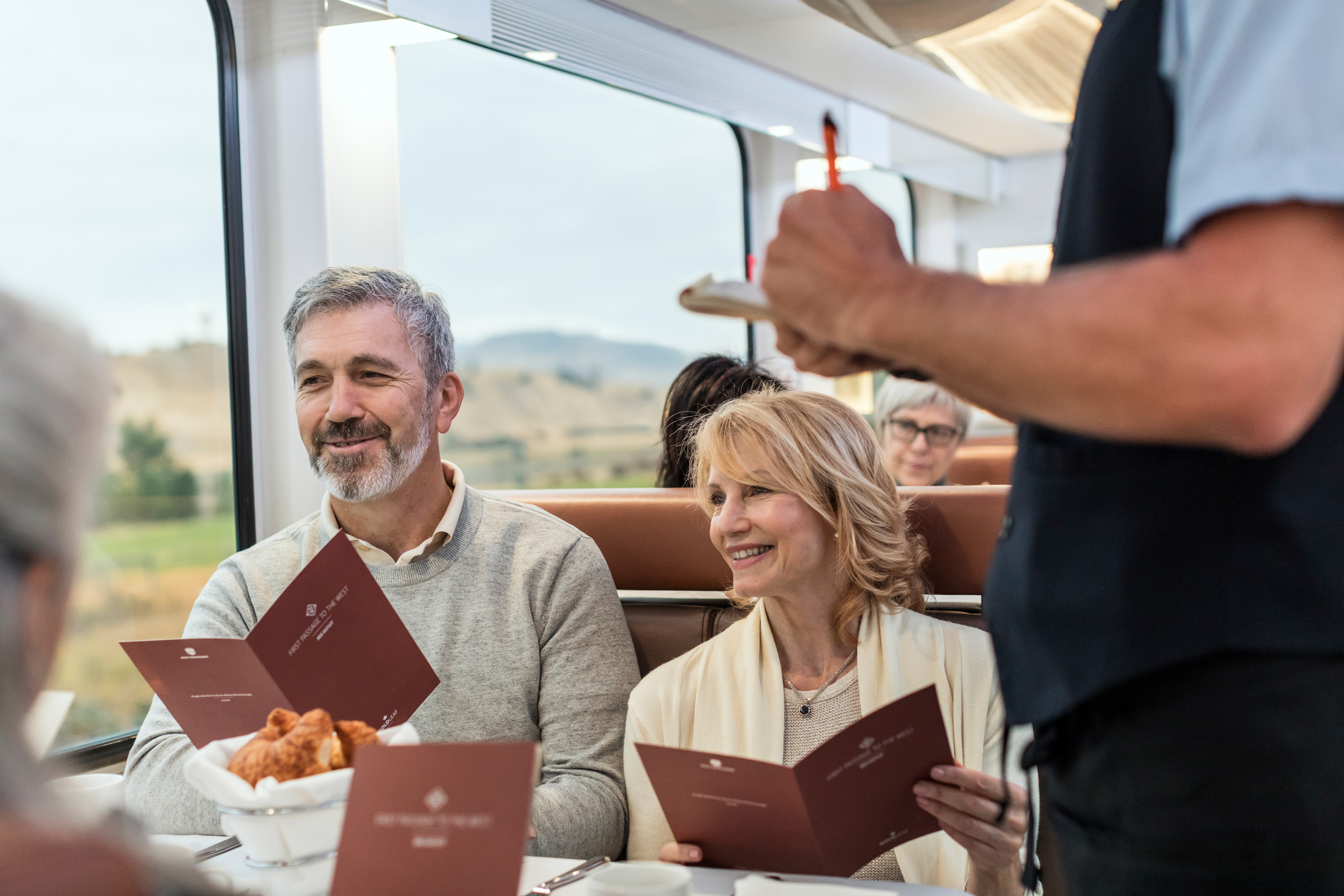 Onboard host taking meal order from guests in the GoldLeaf dining room