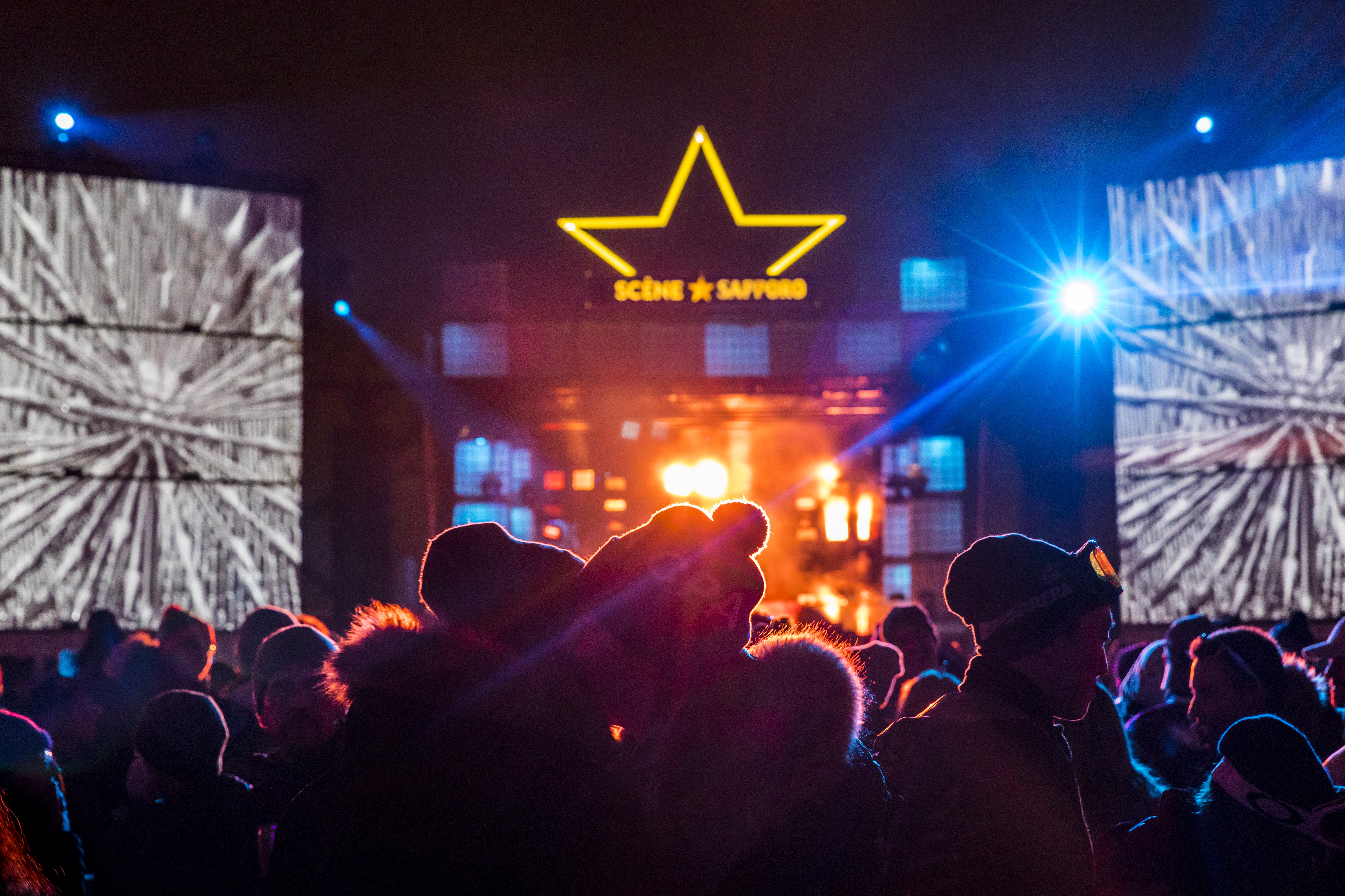 Lights shining on a crowd in front of a music stage at Igloofest