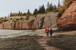 Elderly couple take a walk along the ocean floor by eroded sandstone caves in the Bay of Fundy, at low tide, in Atlantic Canada