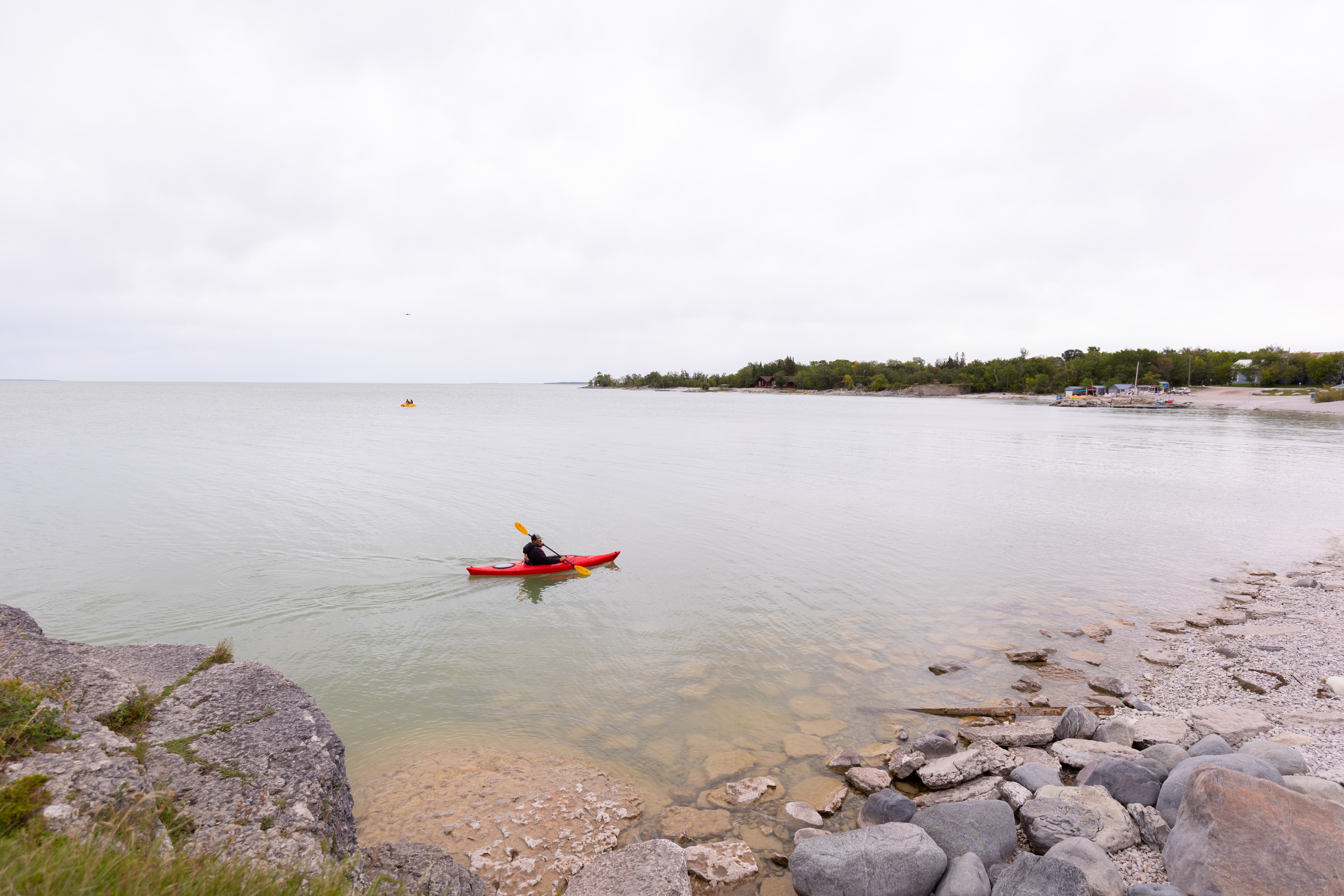 A kayaker paddling on Lake Manitoba on a cloudy day