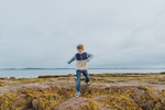 Young boy leaps on ocean floor at low tide in, Ministers Island, a National Historic Site of Canada near Saint Andrews