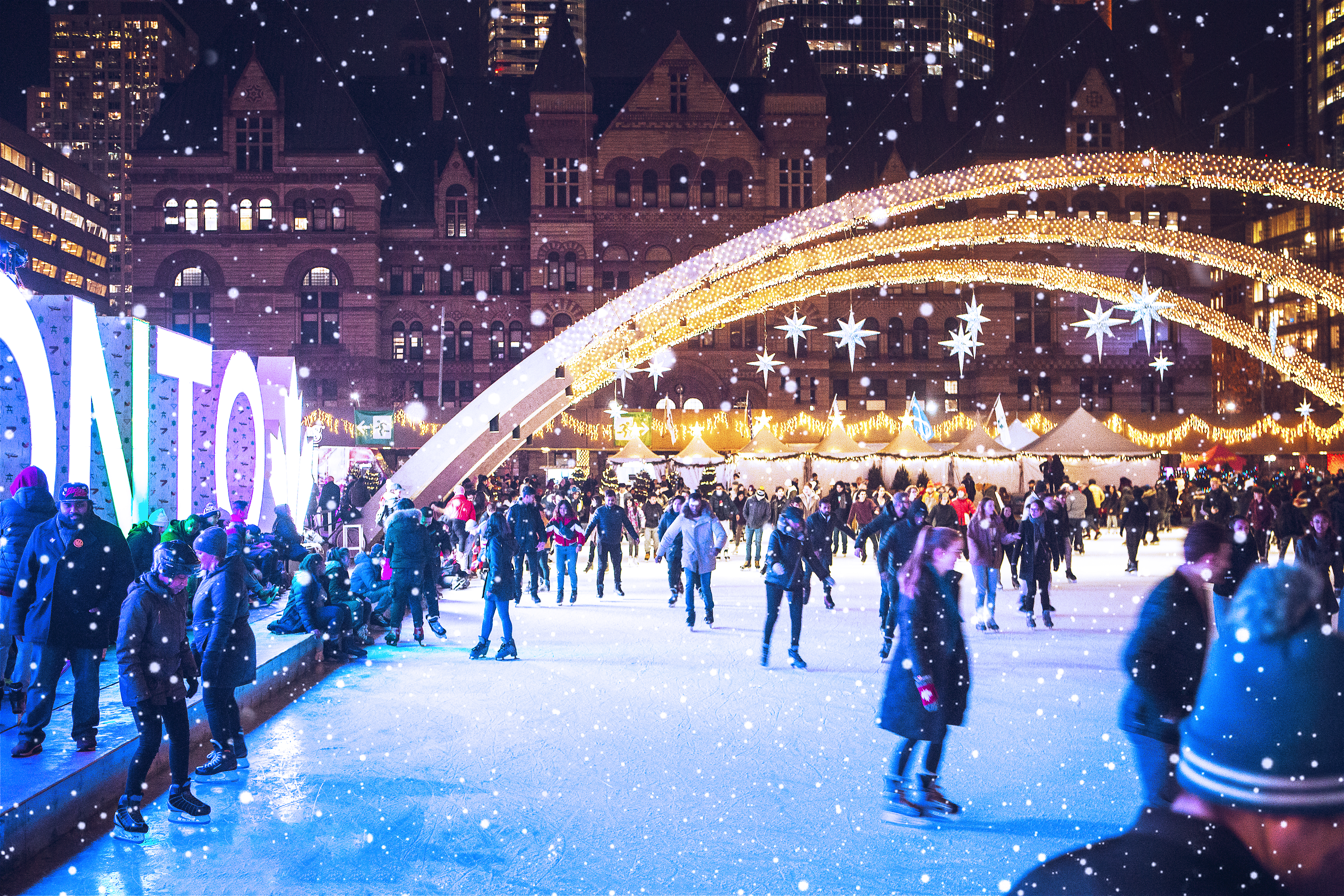 People skating in an outdoor public square next to a large Toronto sign