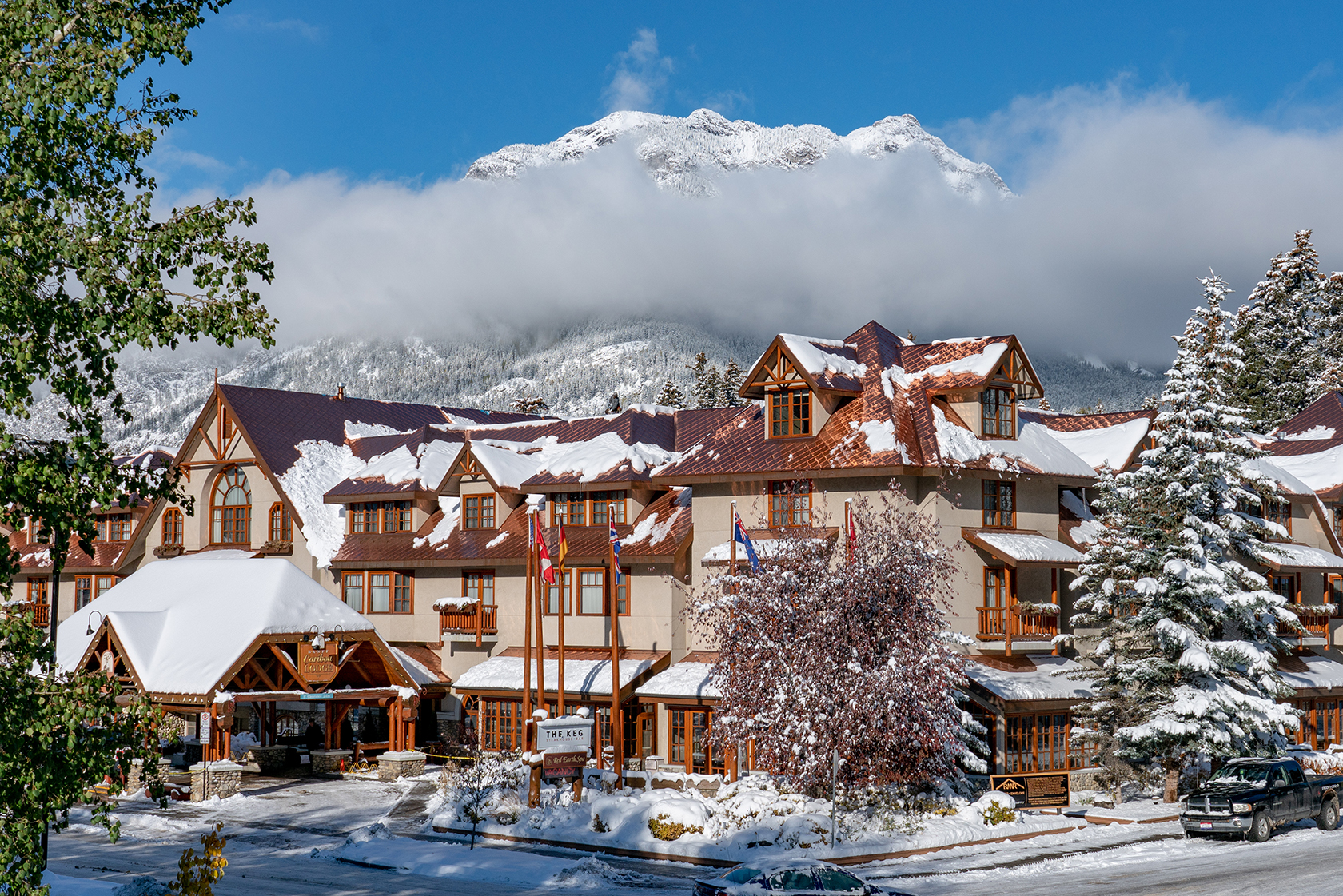Banff Caribou Lodge in the winter with snowy mountains in the background and snow-lined streets