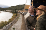 Two people look at the Rocky Mountains from the Rocky Mountaineer outdoor viewing platform 