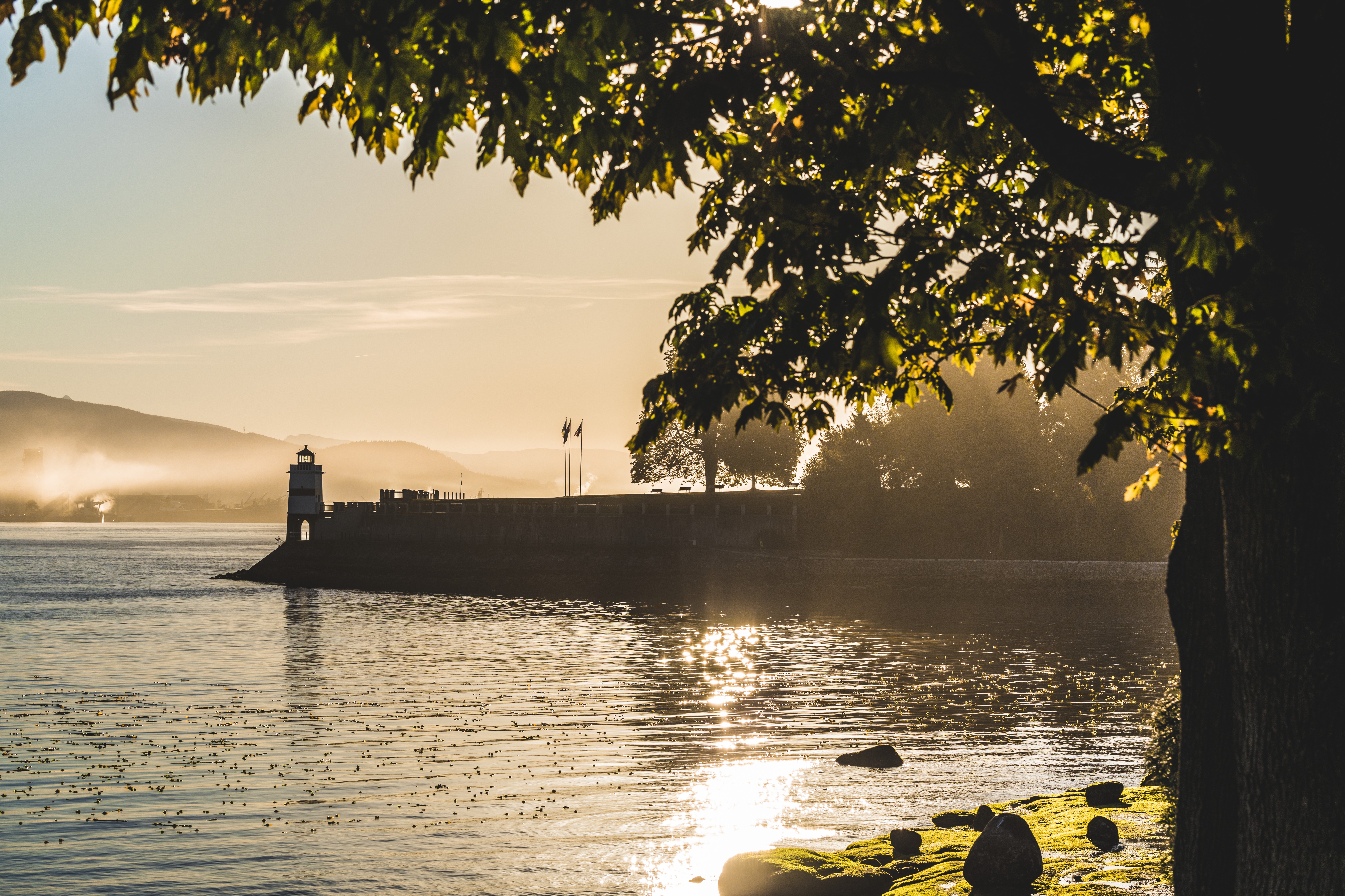 Sunrise over the water, seawall and lighthouse in Stanley Park