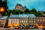 A view of a lively street in Old Quebec City and row of buildings with historic Chateau Frontenac in sight