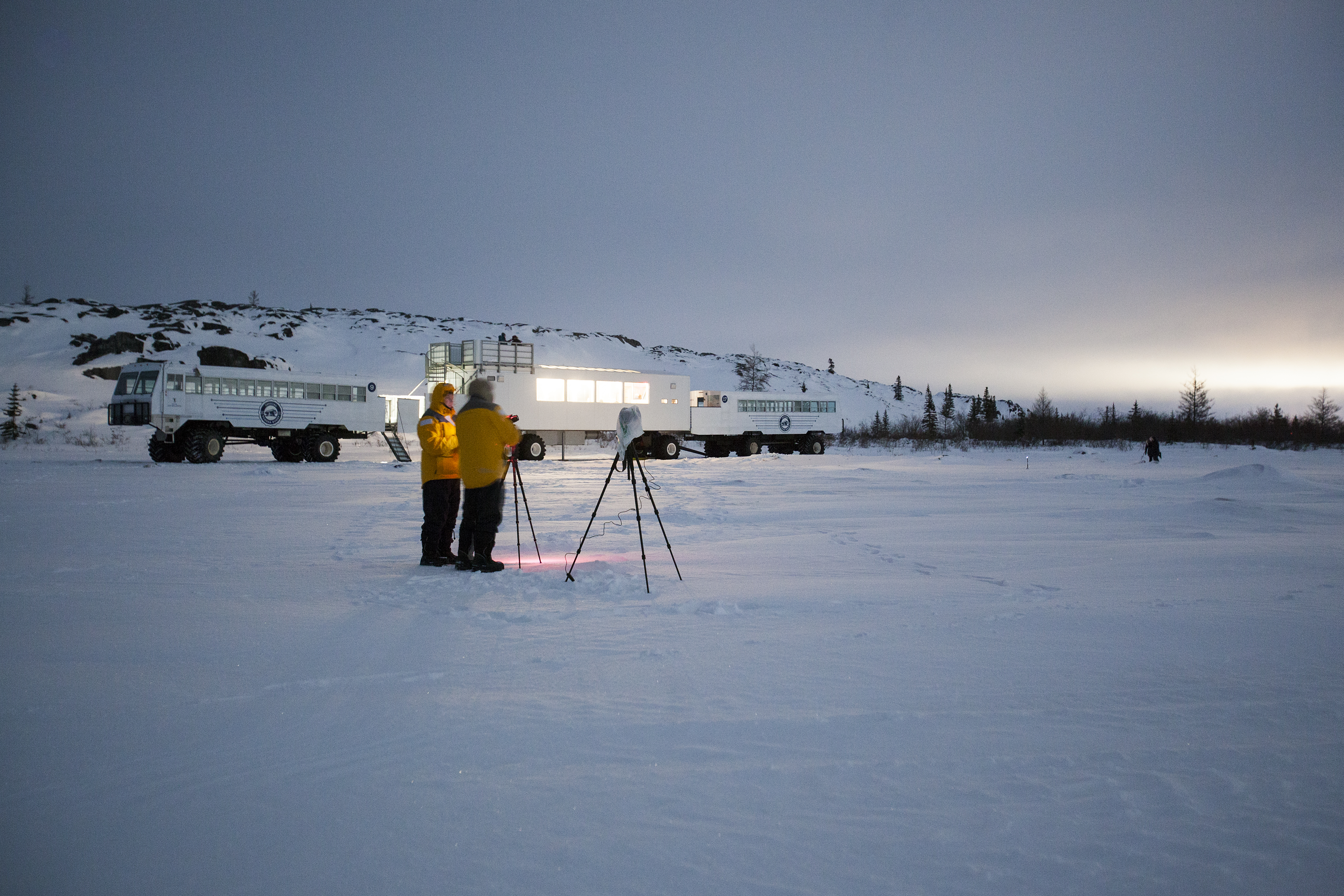A guest receives photography tips from a Photo Specialist guide at Thanadelthur Lounge as the sun sets