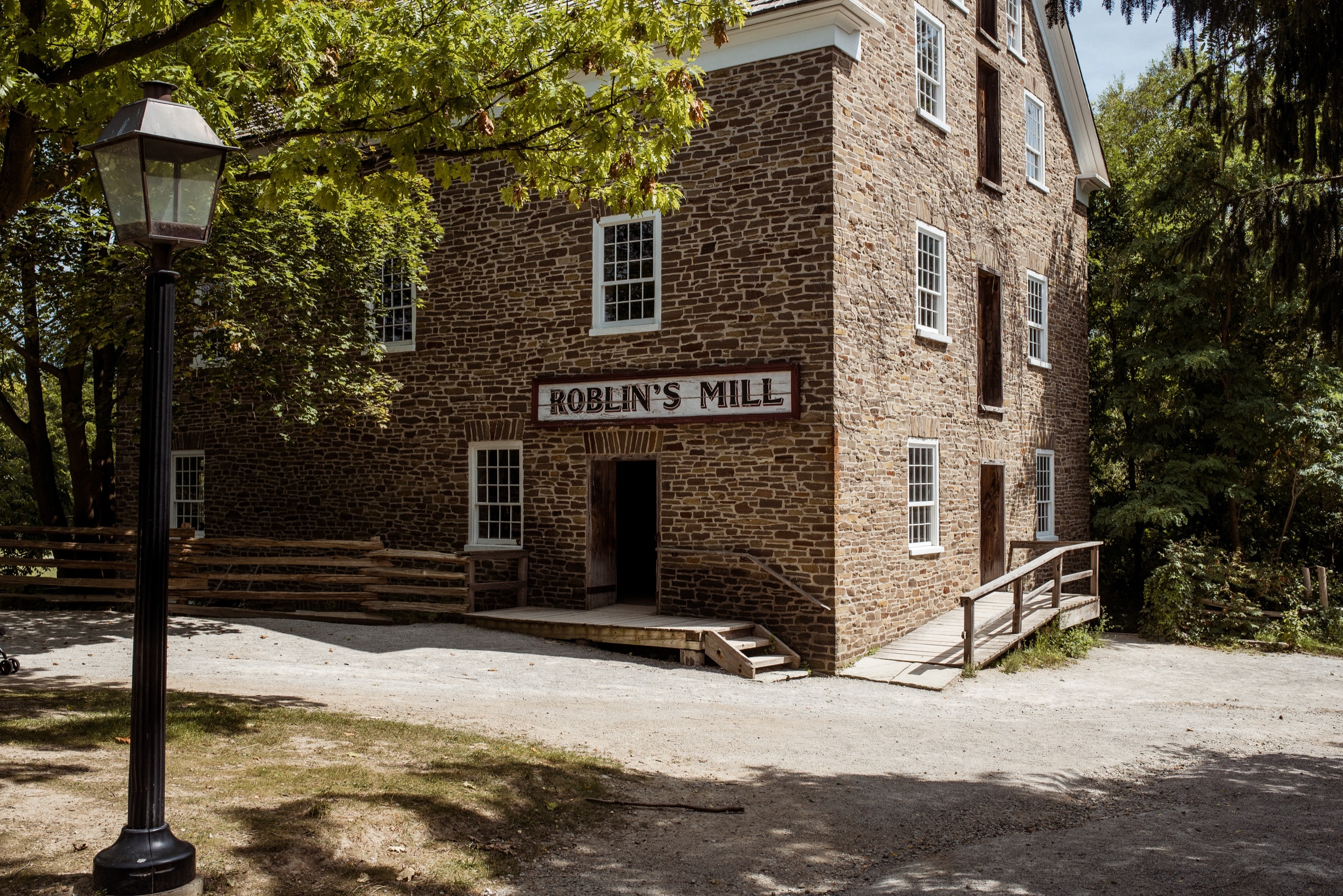 Lamppost and trees outside a brick building with Roblin's Mill signage
