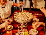 Small group of people sharing a platter of oysters with lemon