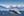 Breaching humpback whale against snow capped mountains seen in the distance in Glacier Bay, Alaska.