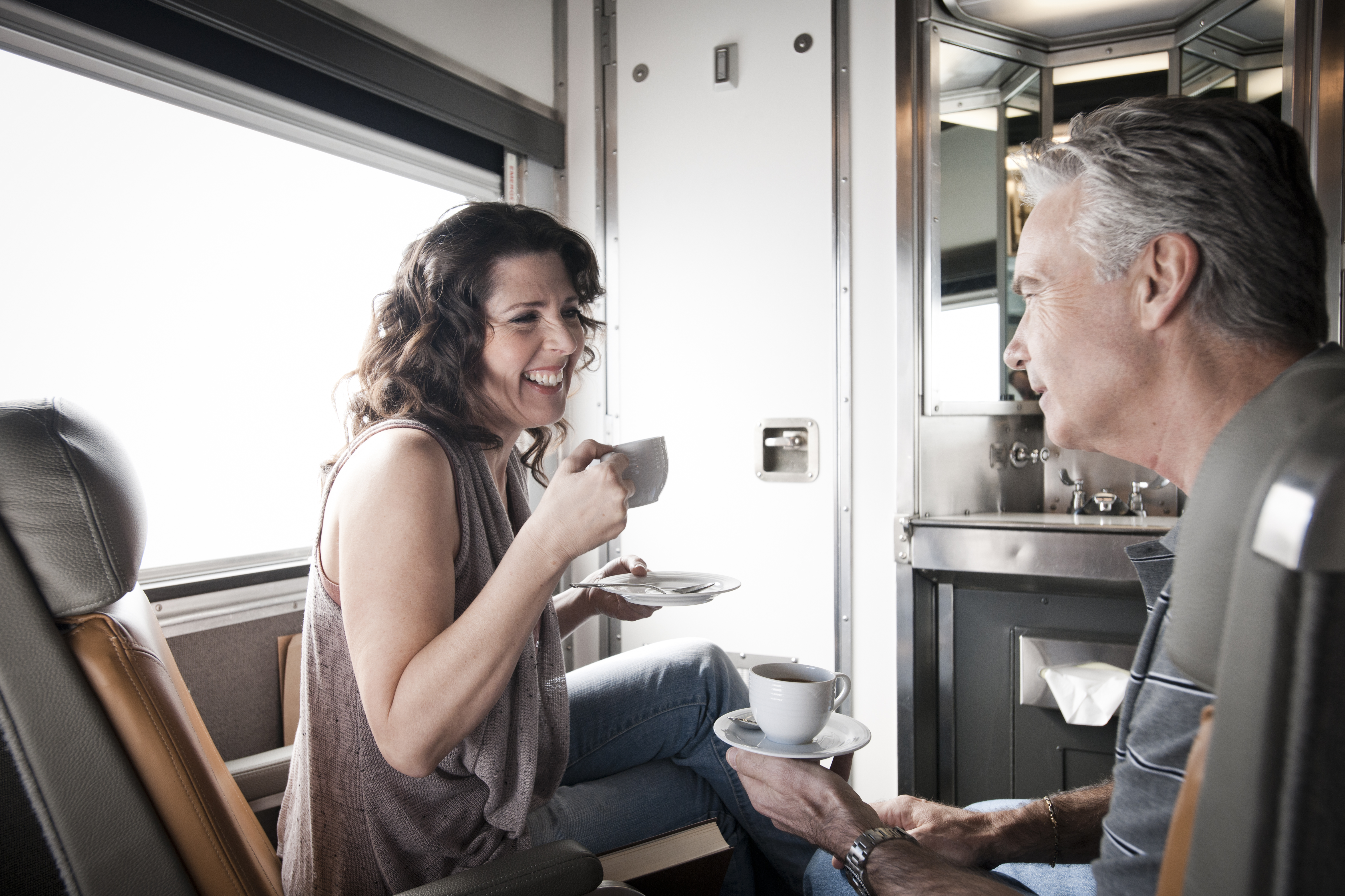 A man and woman enjoy a cup of coffee in a Cabin for 2 in Sleeper Plus Class