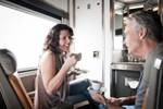 A man and woman enjoy a cup of coffee in a Cabin for 2 in Sleeper Plus Class