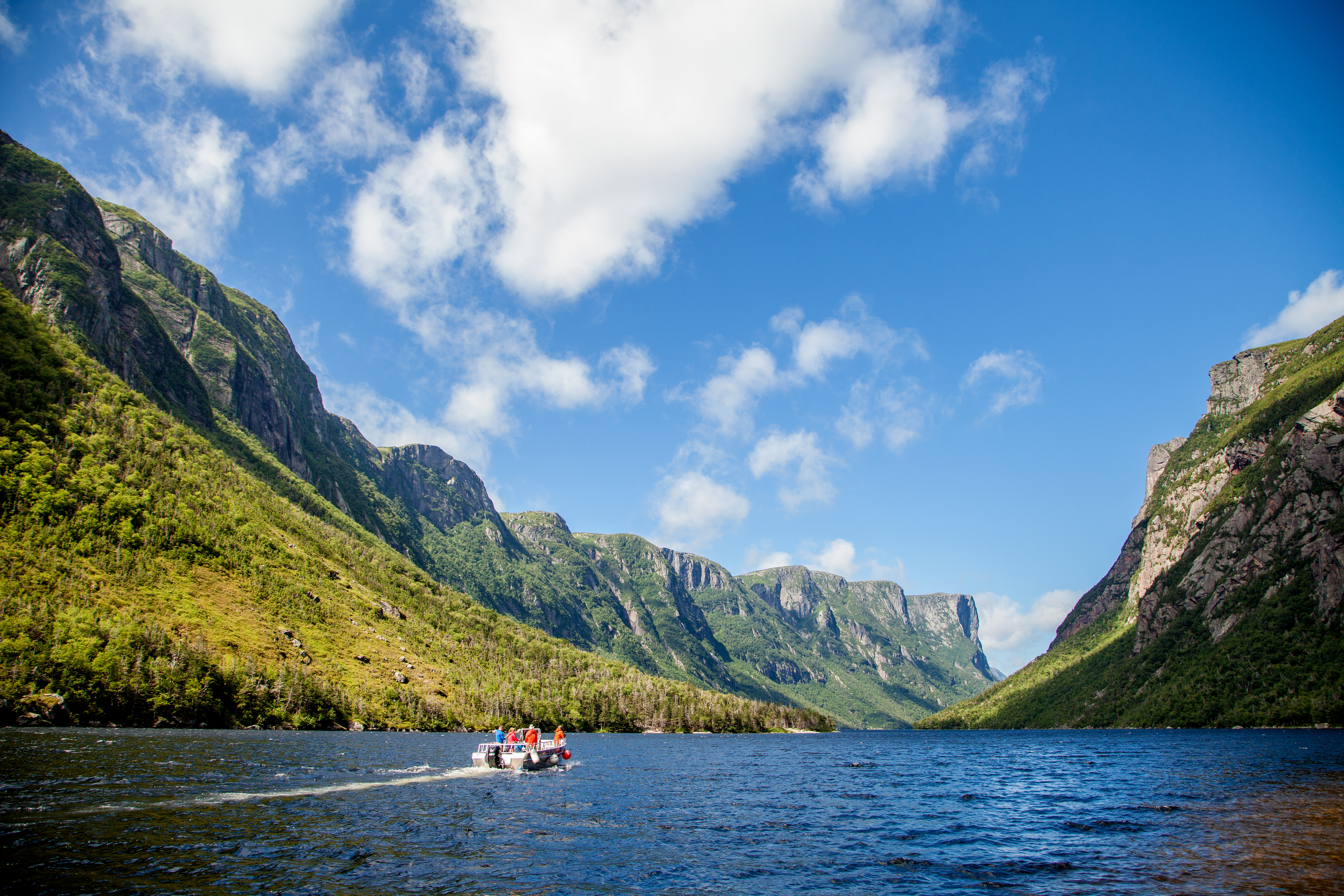 A boat cruises across Western Brook Pond Fjord in Gros Morne National Park
