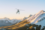 Helicopter flies over Canadian Rockies’ snow-capped mountains peaks