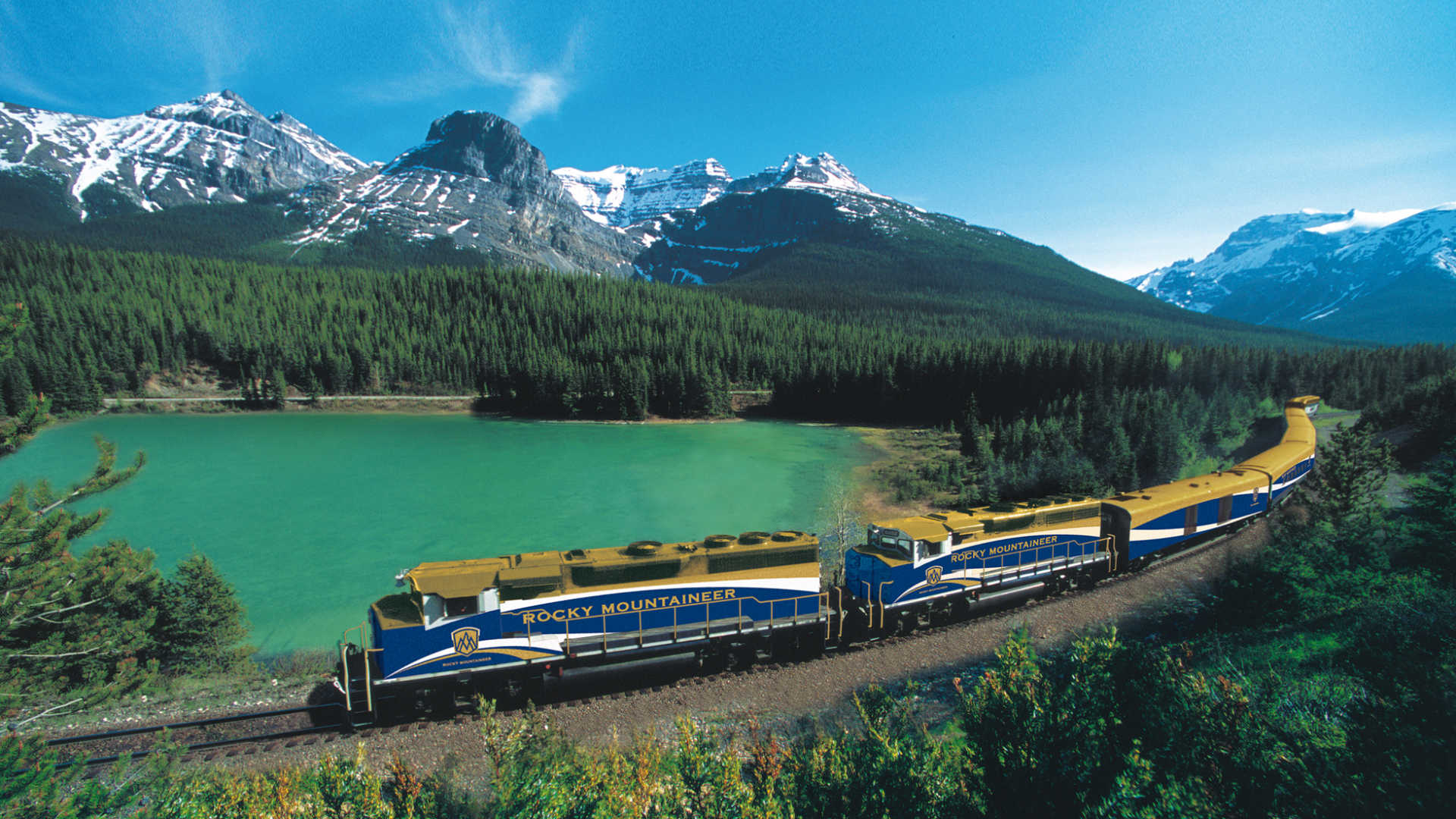Rocky Mountaineer train running through mountains and lake