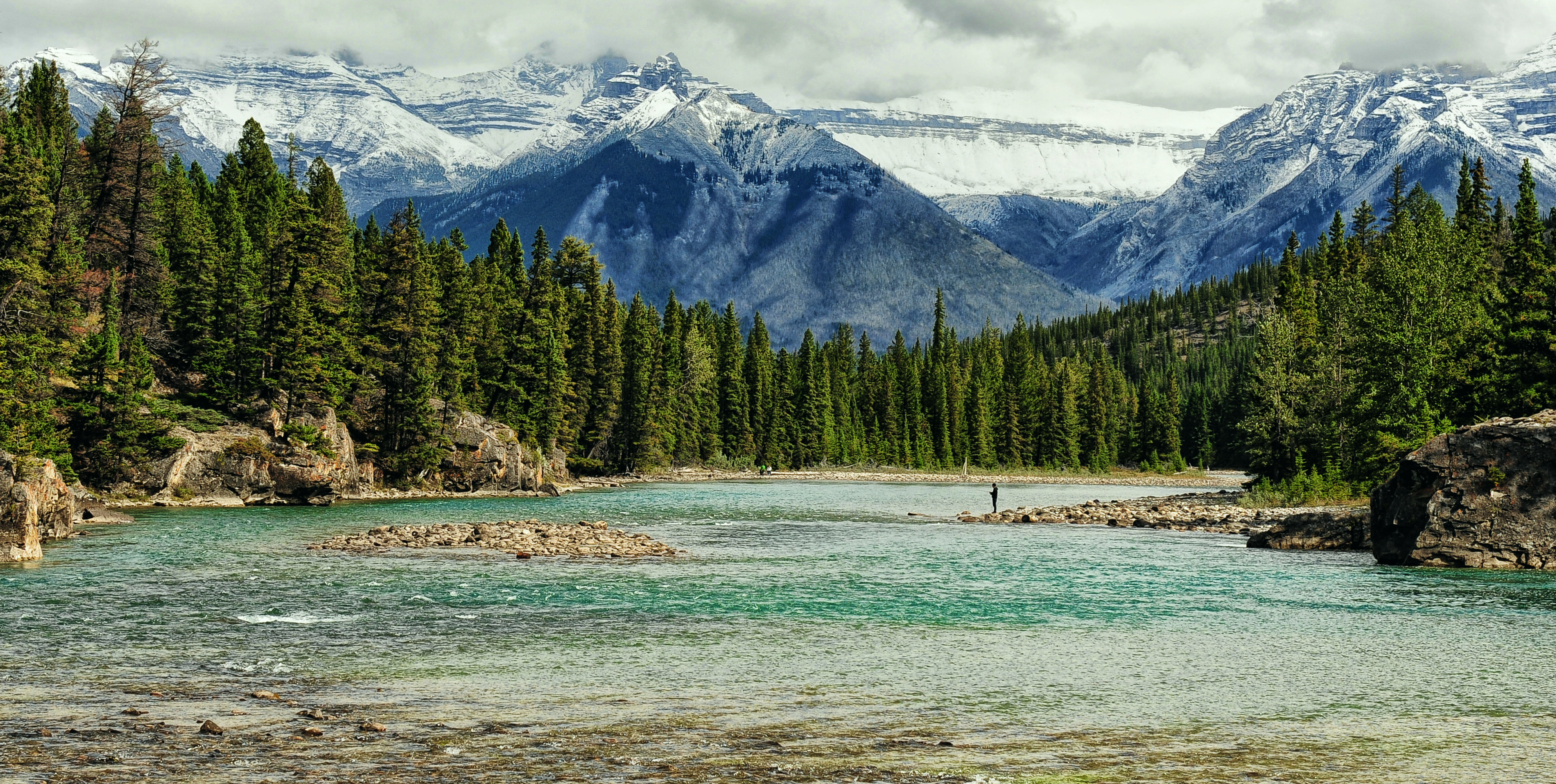 A lone fisherman fishes alongside the Bow River in Banff National Park, Alberta
