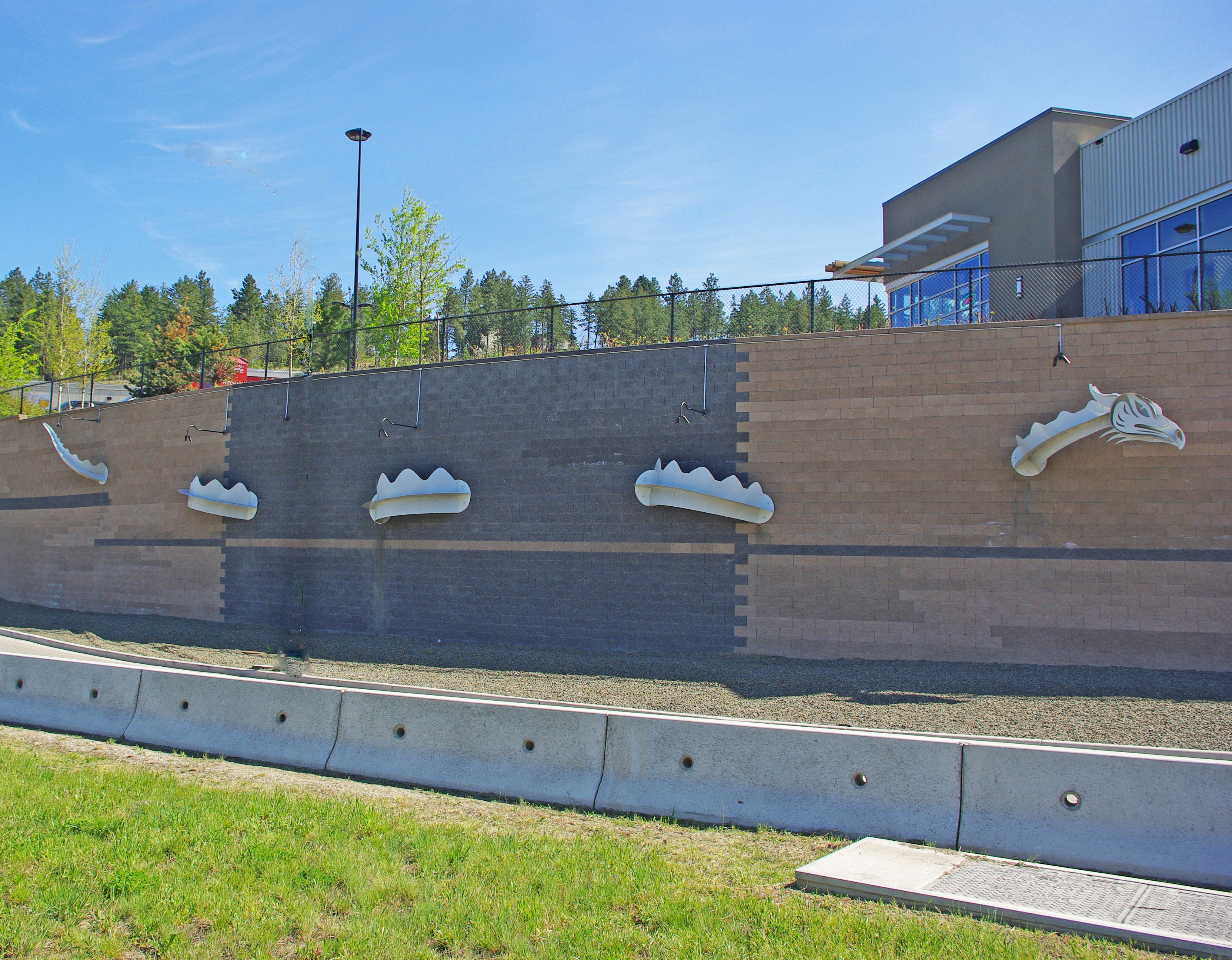 Metal Ogopogo sculpture on a brick wall in West Kelowna