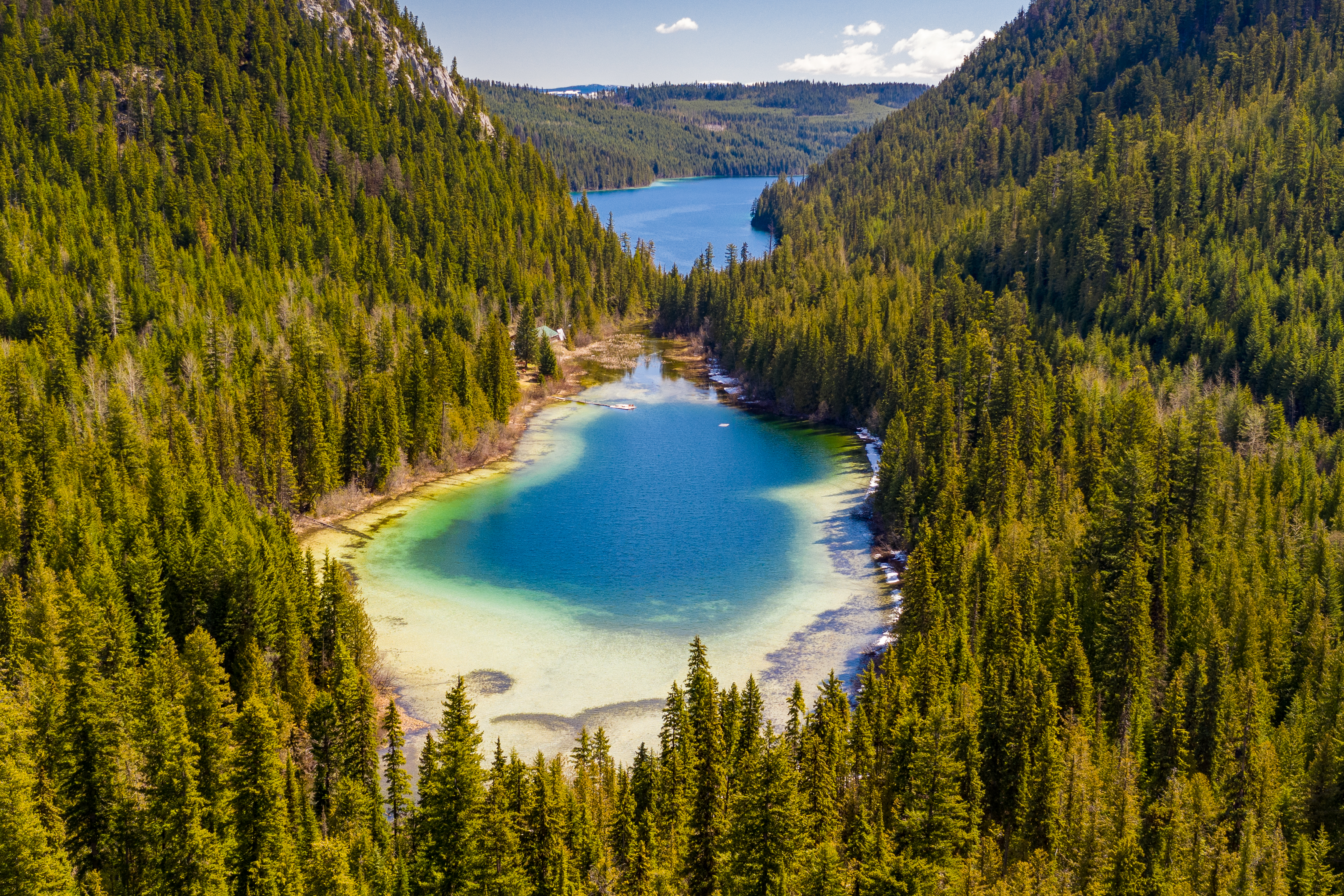 Shallow clear azure lake surrounded by lush forest in British Columbia