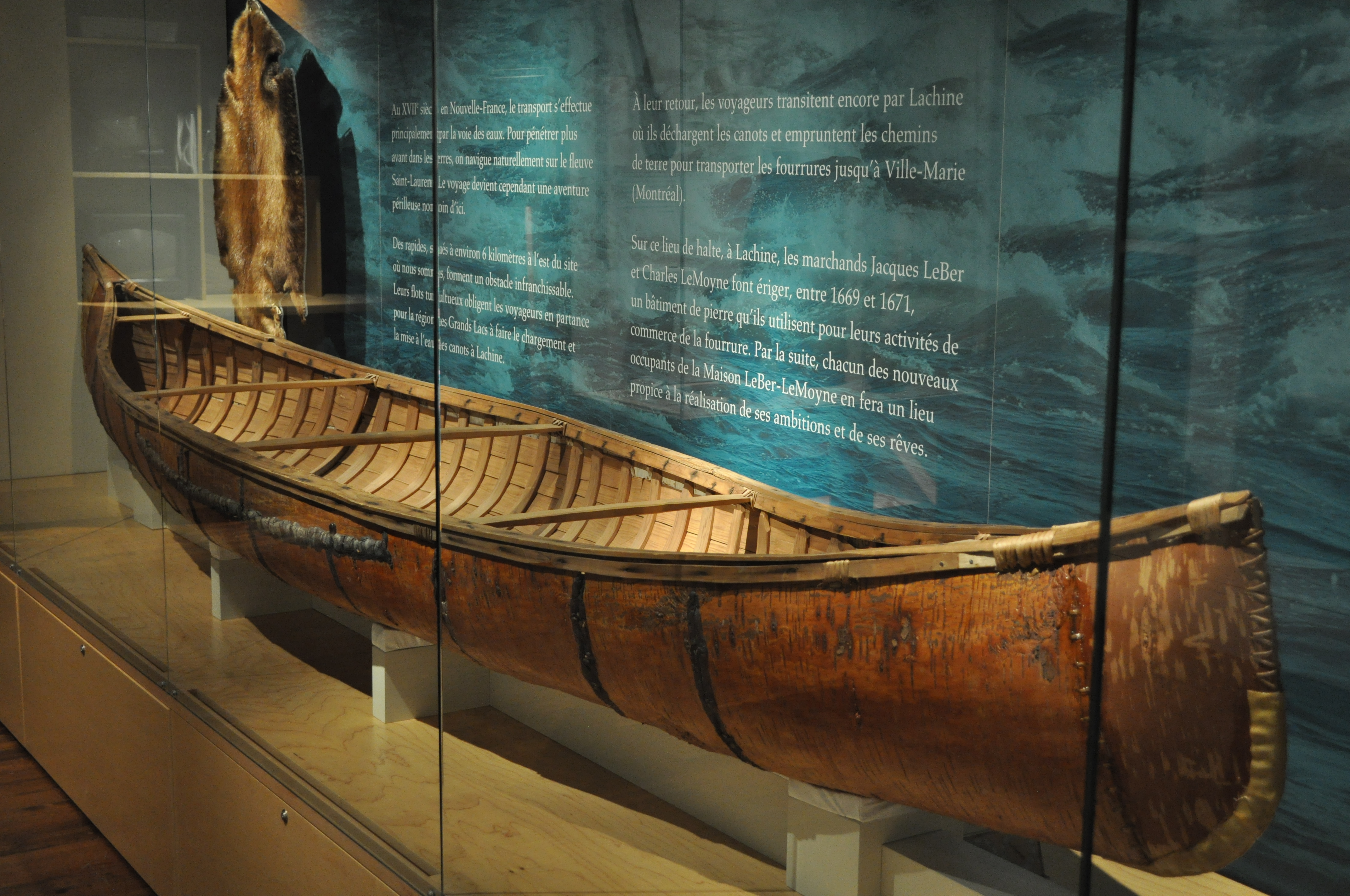 An old wooden canoe in a glass display case in the