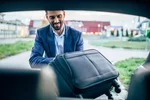 Man packing luggage suitcase into the back of a car