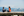 Two women sitting on a log at Jericho beach with Vancouver city skyline behind