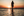 Woman faces horizon and stands in shallow saltwater of Aboiteau Beach at sunset
