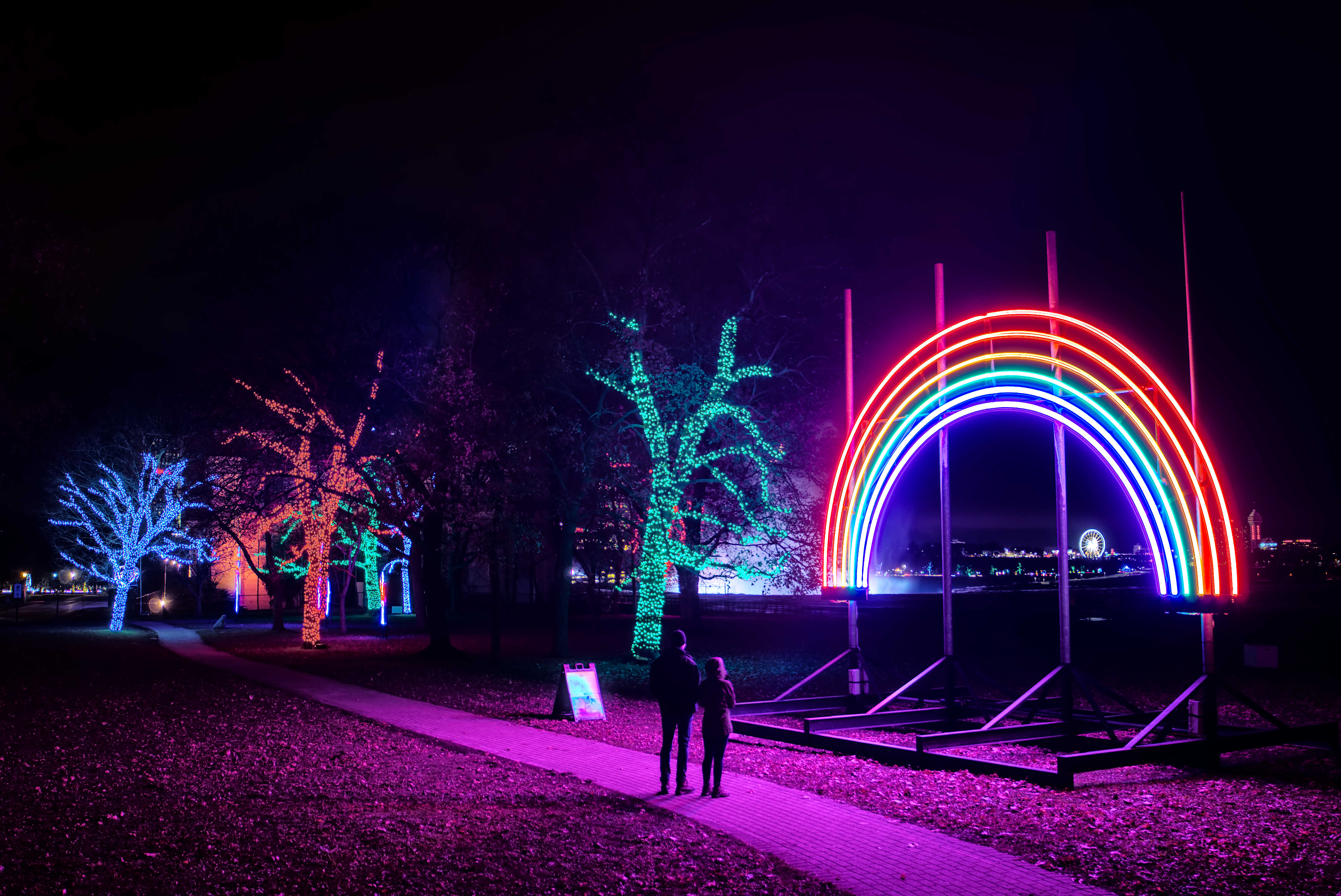 A couple look at rainbow light display at night during the Niagara Falls Festival of Lights   