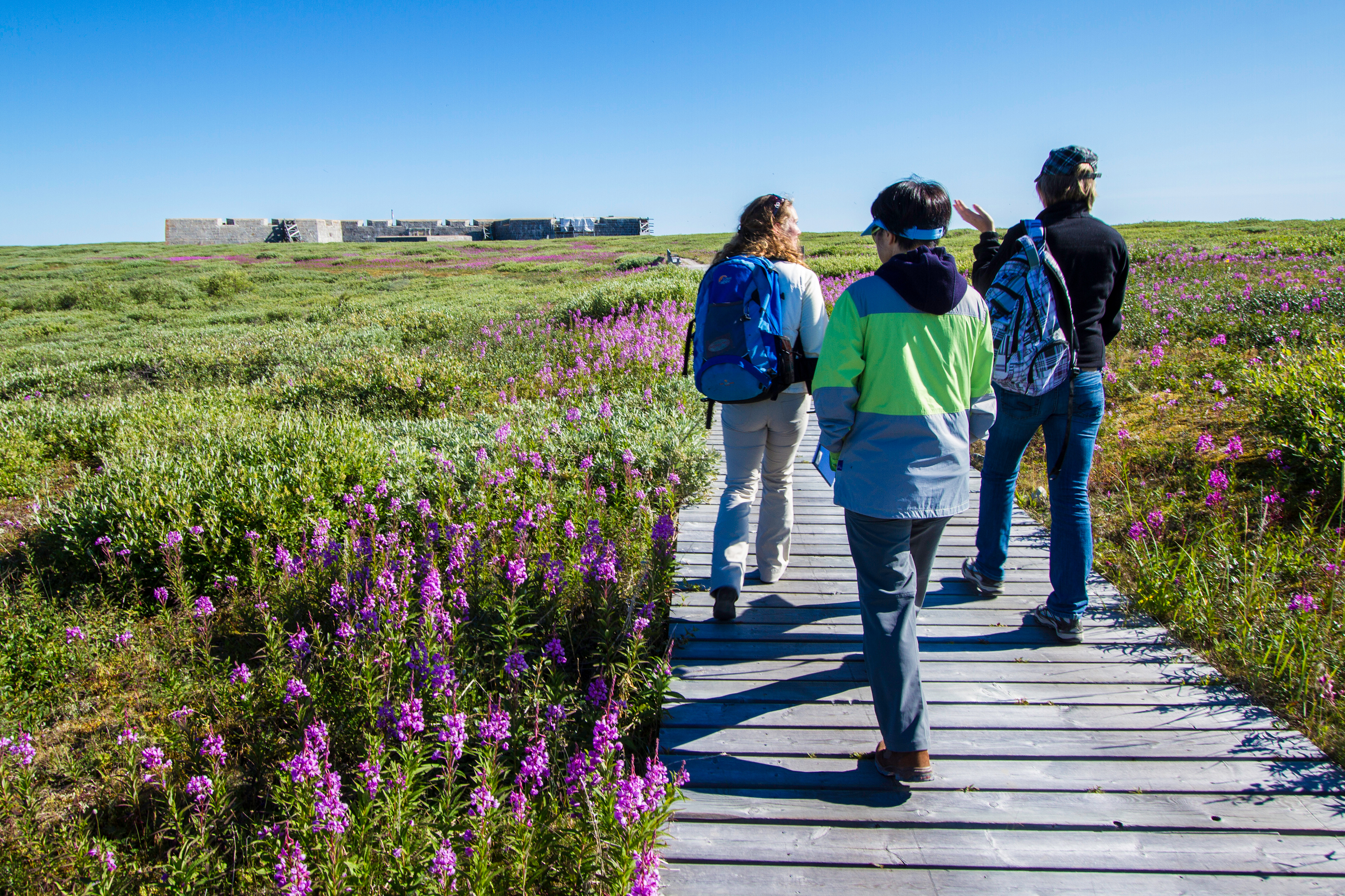 Three people walking along a boardwalk towards the Prince of Wales Fort in Churchill Manitoba