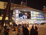 Crowds of people outside of the Scotiabank Arena while a Toronto Maple Leafs NHL hockey game plays on a large digital screen