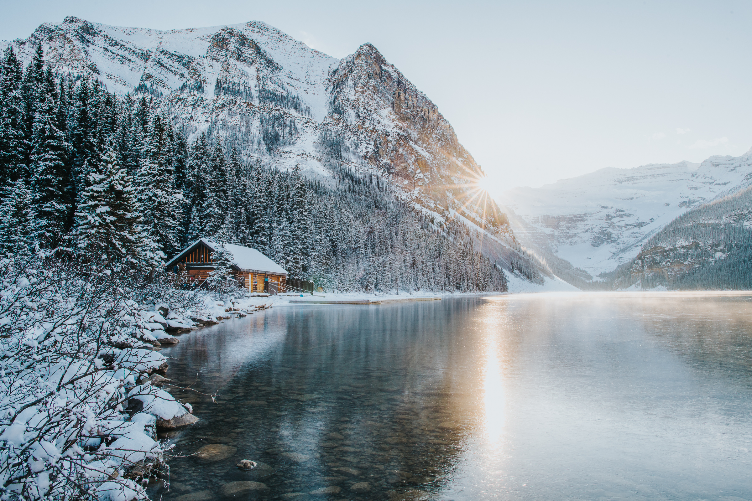 Sunset in Lake Louise in winter with boat and canoe cabin by the lake with mountains behind