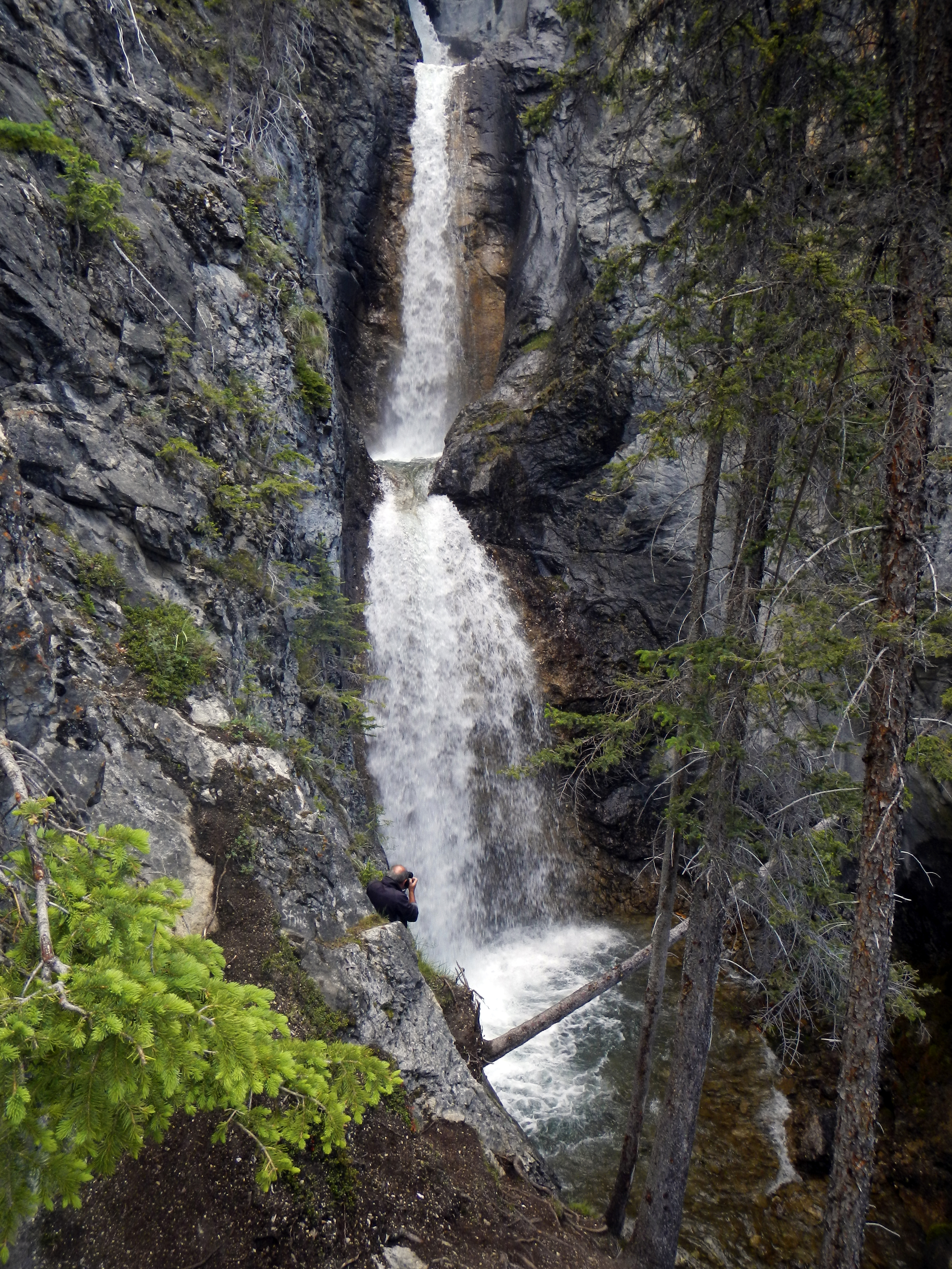 Man taking photo of Silverton Falls with height of fifty meters from rocky viewing point