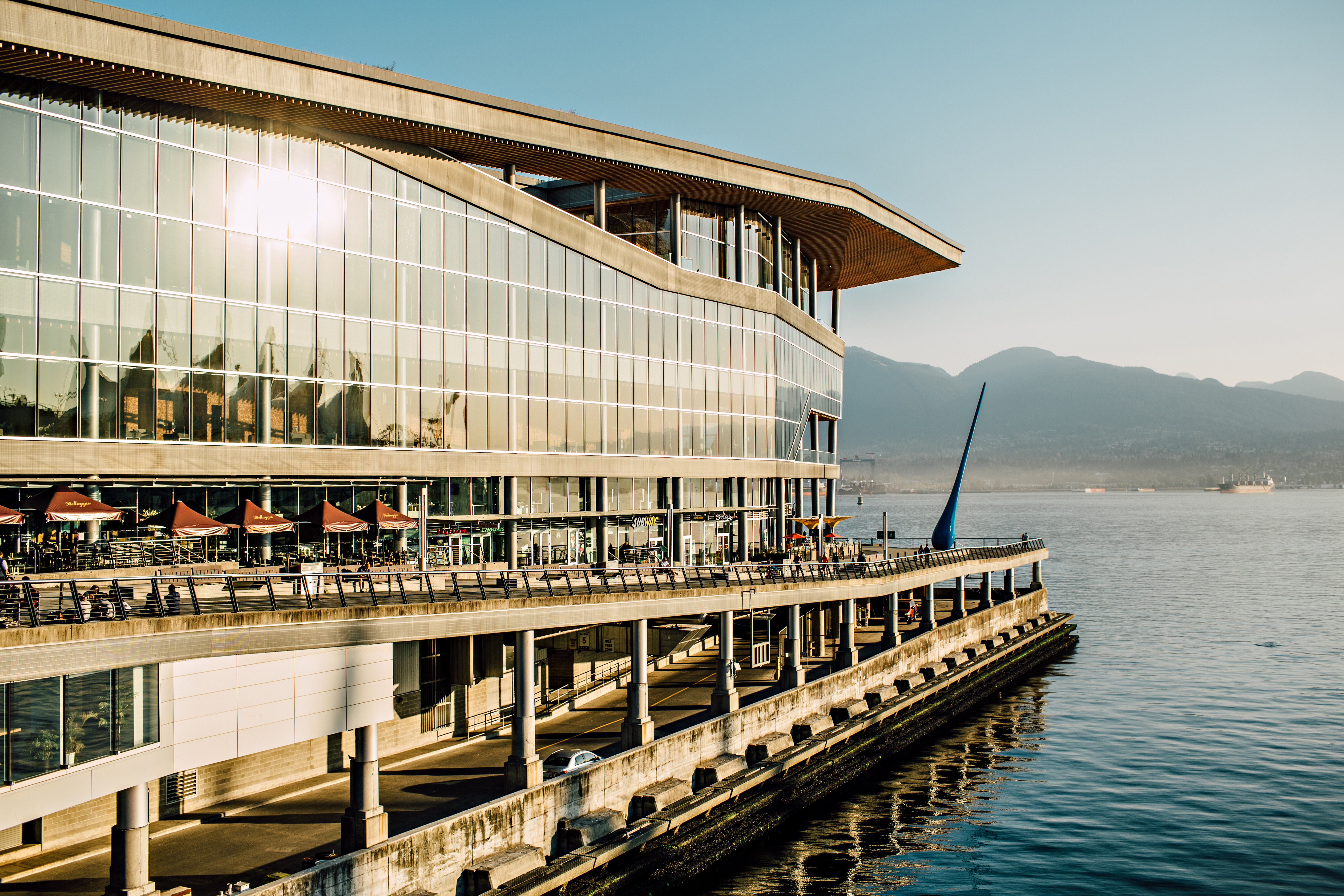Sun shining on the Vancouver Convention Centre with mountains and ocean in the background