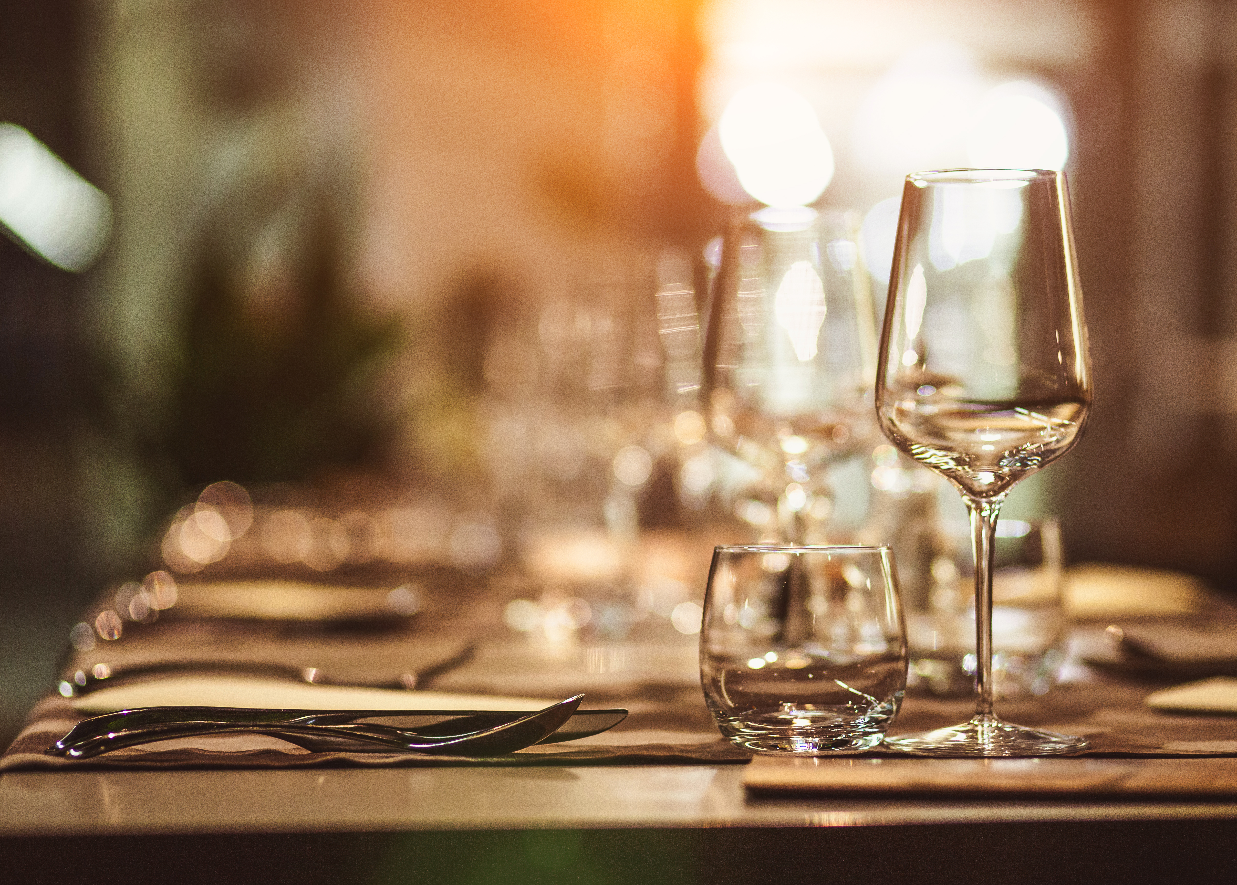 Close up of a table set for dinner with wine glasses, water glasses and cutlery