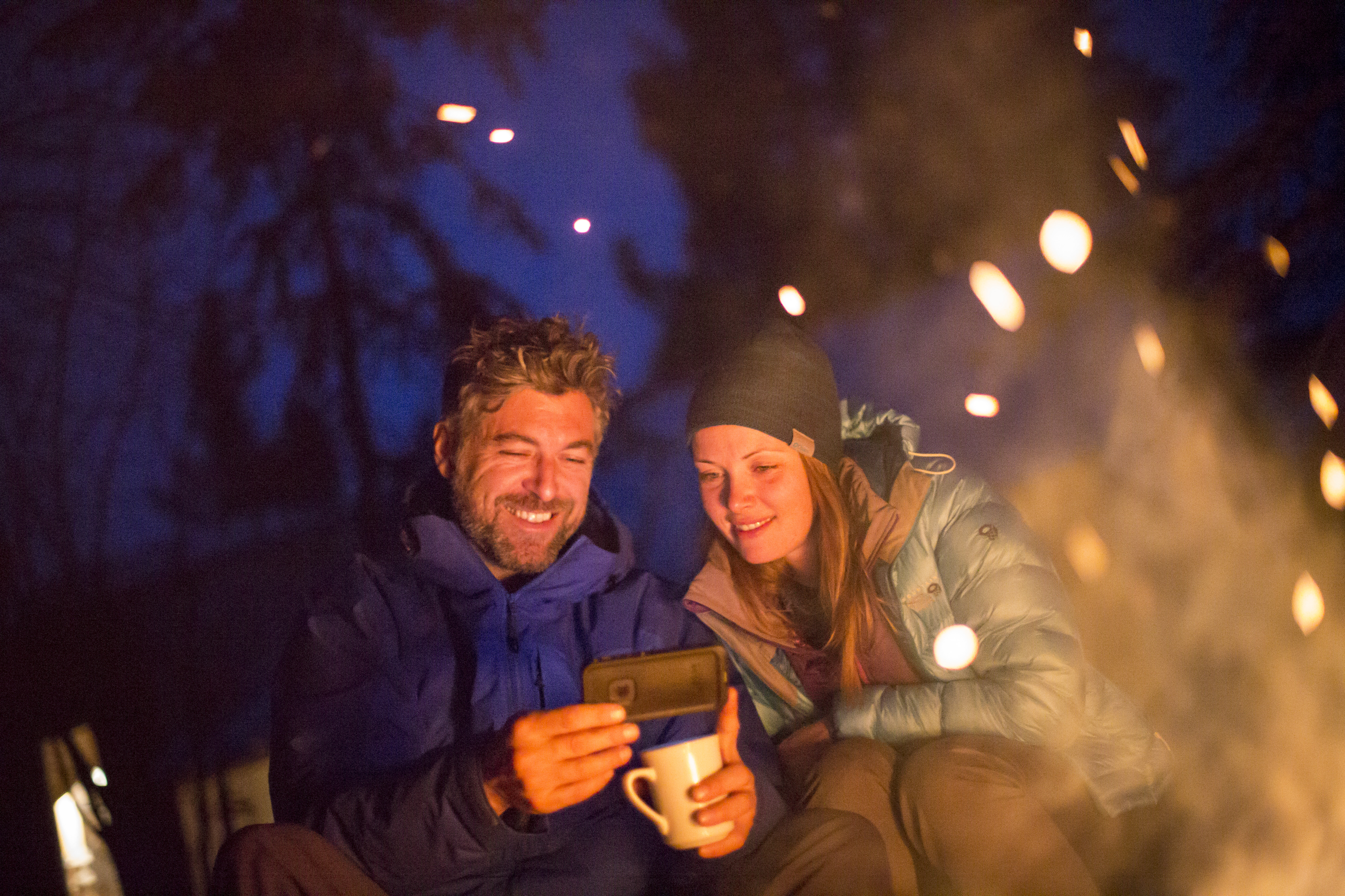 Couple talking behind a campfire on a Yukon Aurora Tours