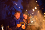 Couple talking behind a campfire on a Yukon Aurora Tours