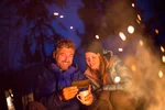 Couple talking behind a campfire on a Yukon Aurora Tours