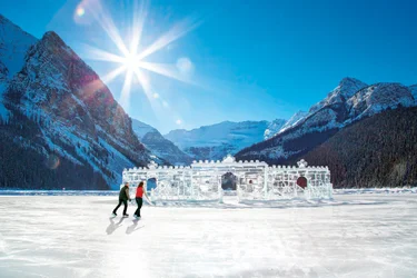 Couple skating past an ice castle in the rockies