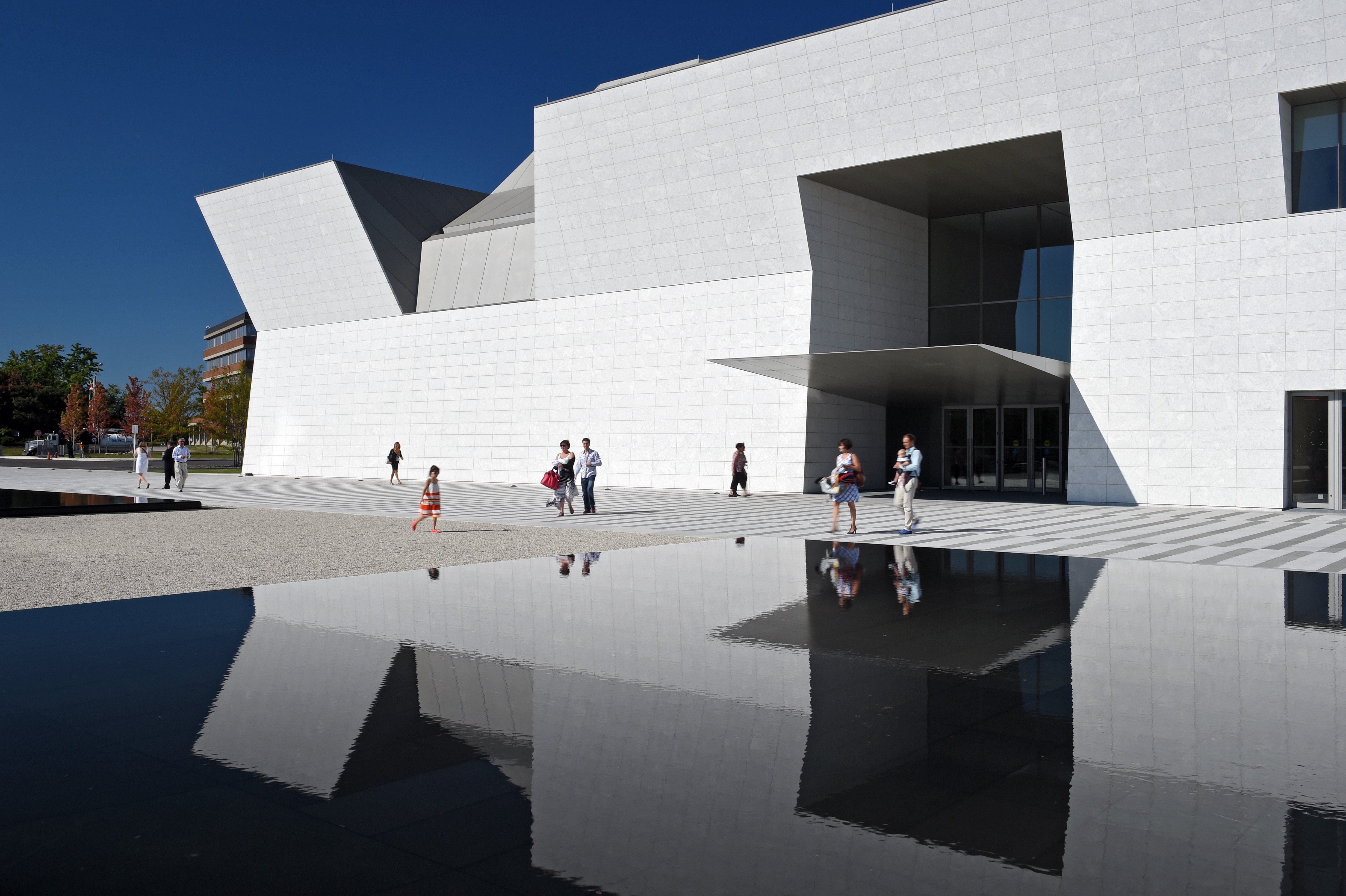 People walking outside the white building and reflecting pools of the Aga Khan Museum