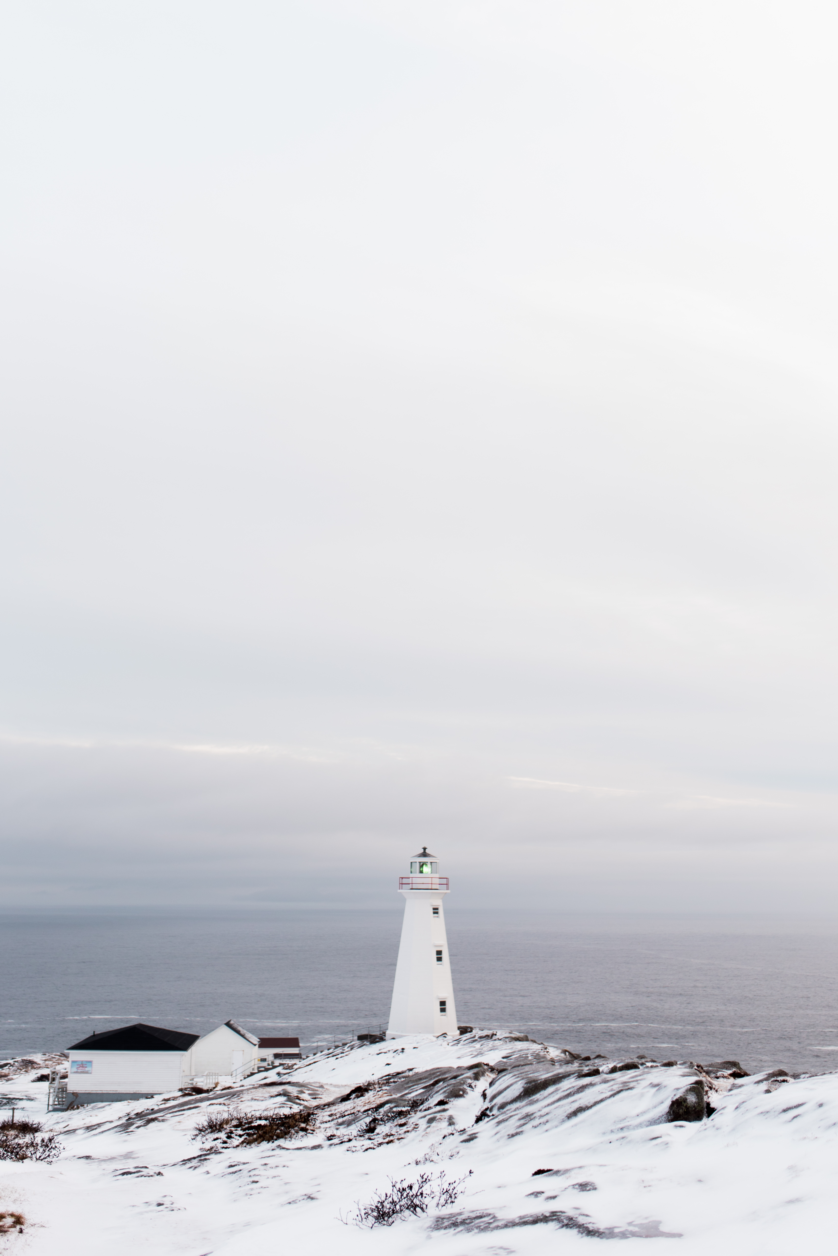 View of lighthouse on snowy cliff with a view of the sea in the distance