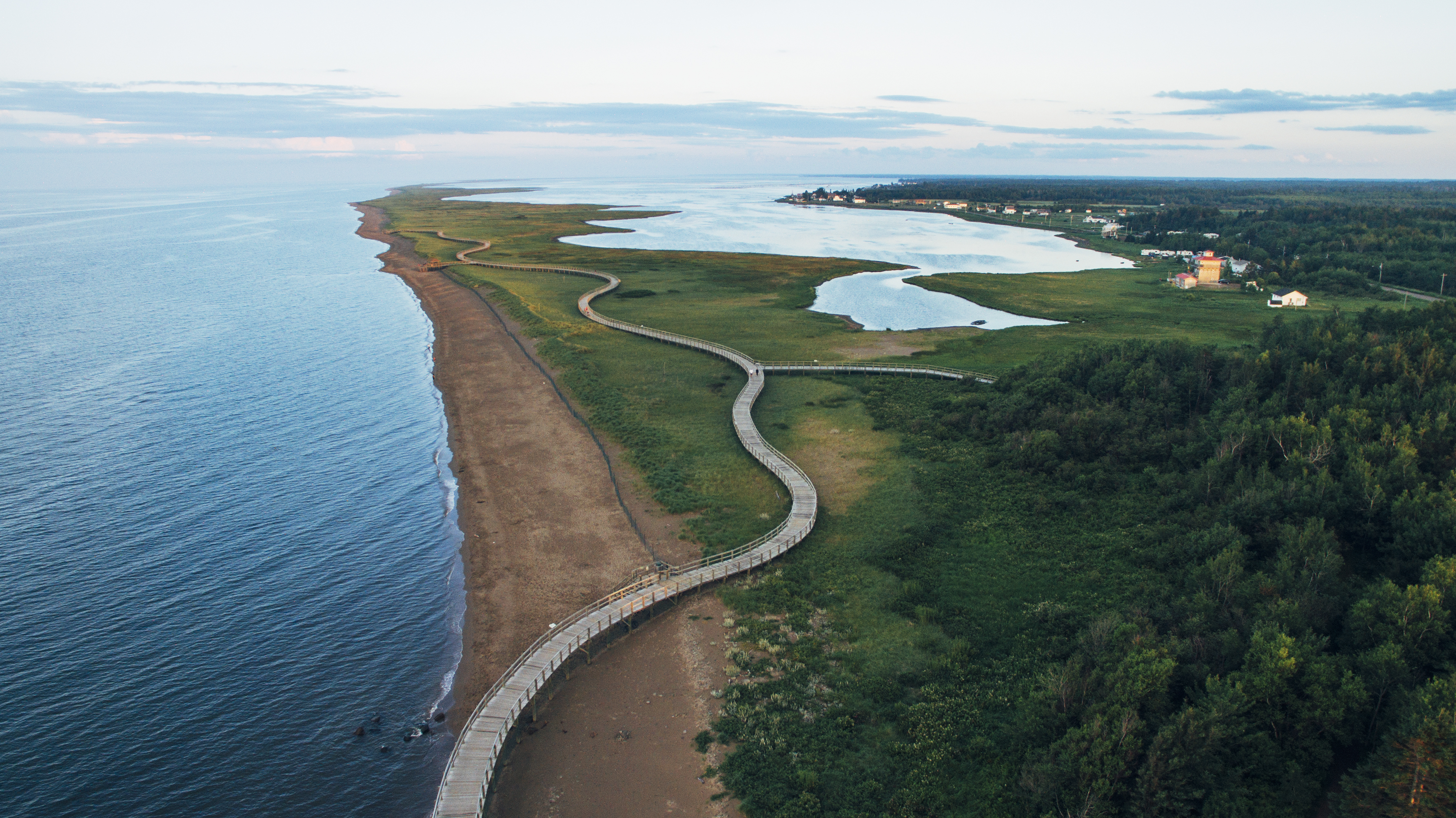 Boardwalk winds through coastal ecological site with natural saltwater beach in New Brunswick